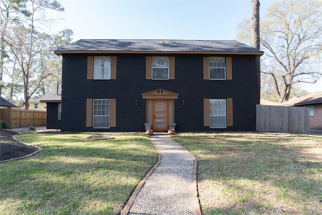 colonial home with a front yard and fence