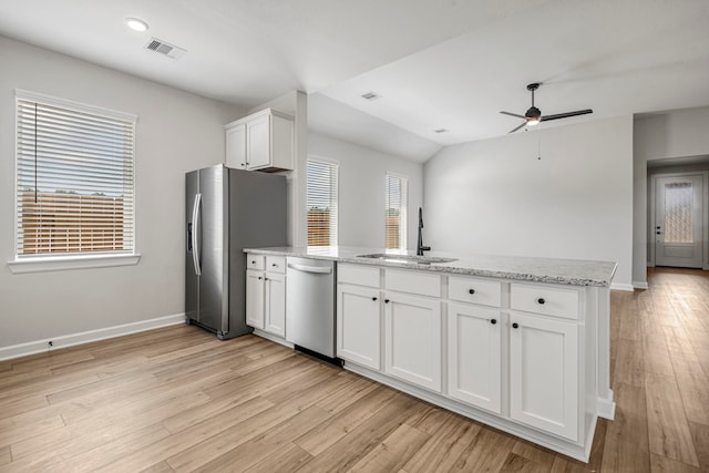 kitchen featuring light stone countertops, light wood finished floors, a sink, appliances with stainless steel finishes, and white cabinetry