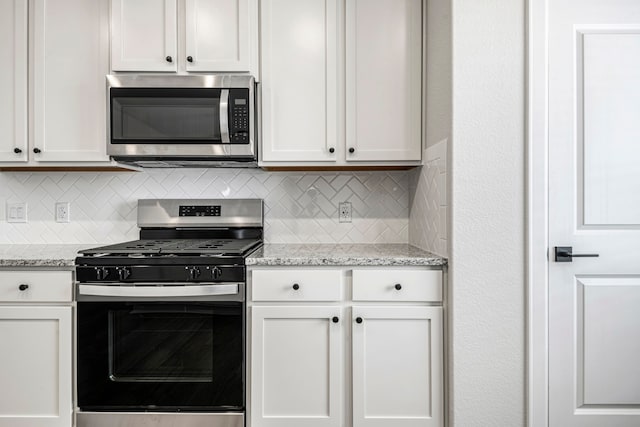 kitchen featuring light stone counters, decorative backsplash, appliances with stainless steel finishes, and white cabinetry