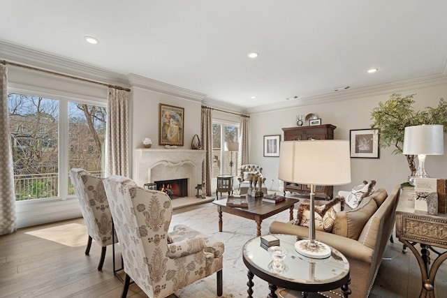 living area with plenty of natural light, light wood-type flooring, a high end fireplace, and ornamental molding