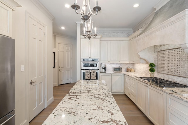 kitchen with wood finished floors, ornamental molding, appliances with stainless steel finishes, backsplash, and a chandelier