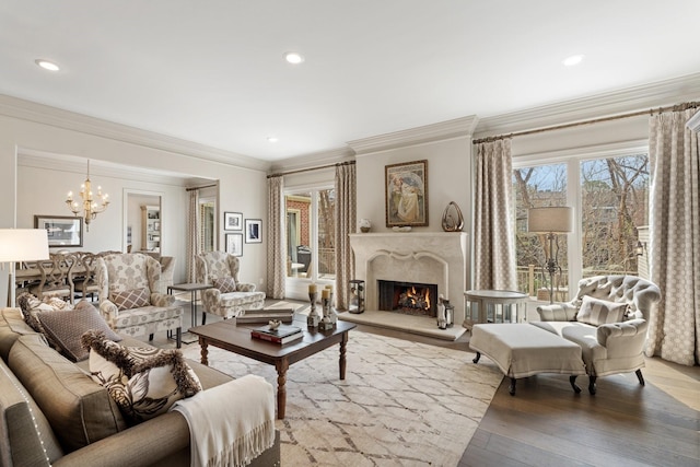 living room with a chandelier, ornamental molding, a high end fireplace, and wood finished floors