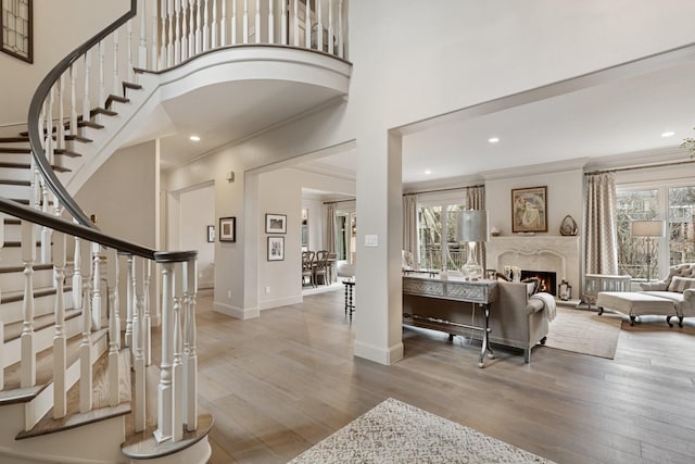 foyer entrance with wood finished floors, baseboards, a towering ceiling, and ornamental molding