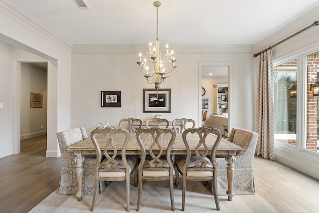 dining area with ornamental molding, visible vents, light wood finished floors, and a chandelier