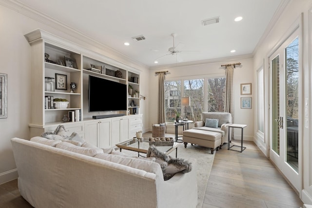 living room with visible vents, ceiling fan, crown molding, and light wood finished floors