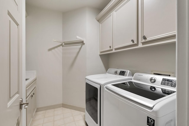 laundry area featuring washer and dryer, baseboards, cabinet space, and light tile patterned floors