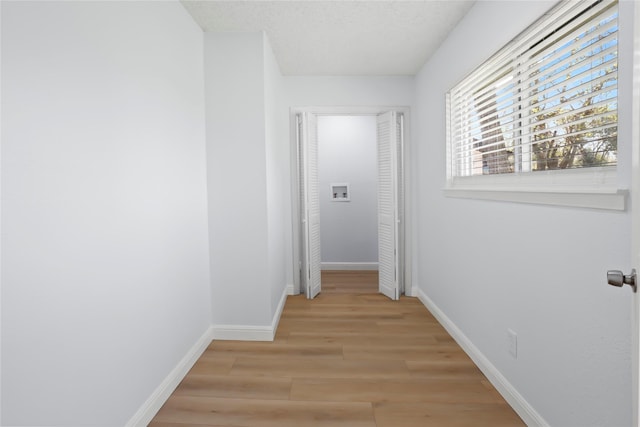 corridor with light wood-style flooring and baseboards