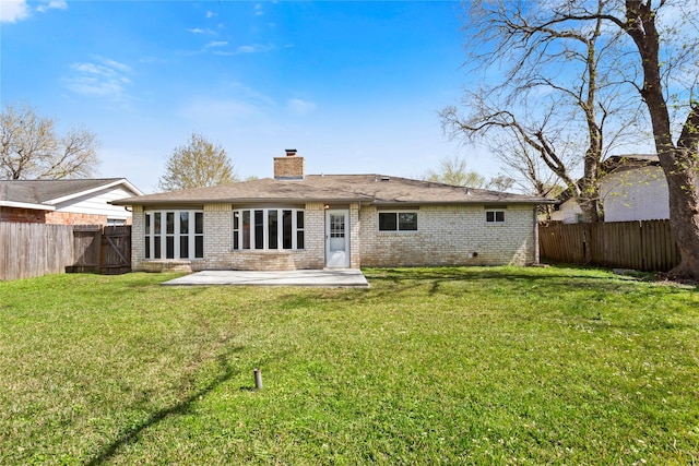 back of property featuring brick siding, a lawn, a chimney, a fenced backyard, and a patio