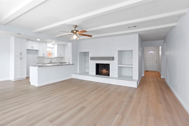 unfurnished living room featuring beamed ceiling, visible vents, baseboards, and ceiling fan