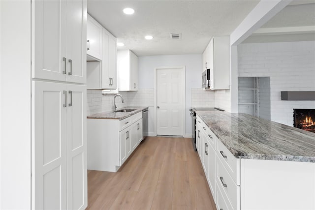 kitchen featuring visible vents, light stone countertops, stainless steel appliances, and a sink