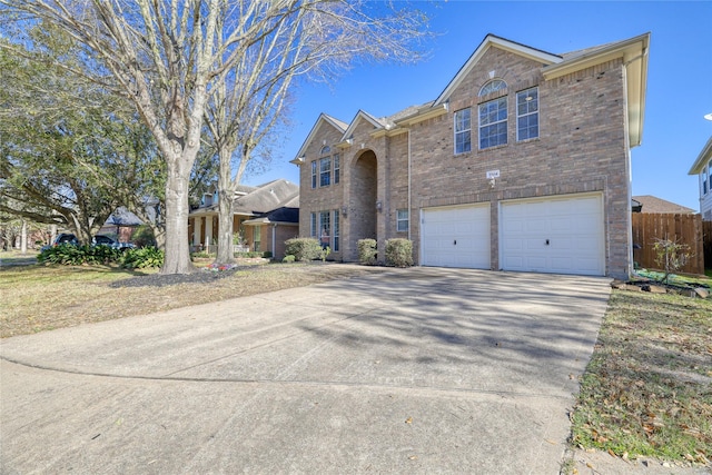 traditional-style house featuring a garage, fence, brick siding, and driveway