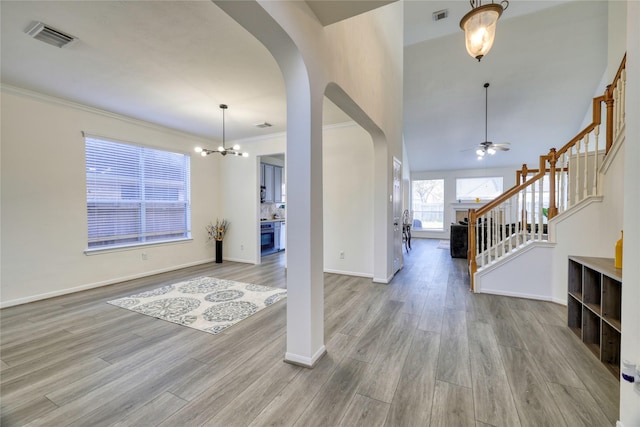 foyer with wood finished floors, stairway, visible vents, and arched walkways