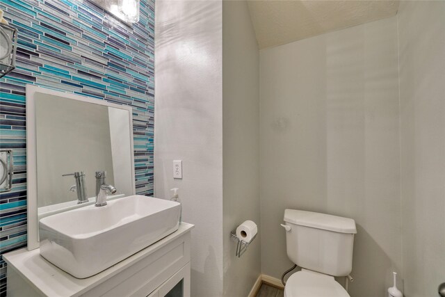 half bath featuring toilet, vanity, and baseboards