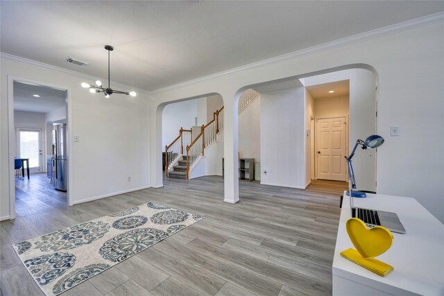 spare room featuring light wood finished floors, visible vents, stairs, ornamental molding, and arched walkways