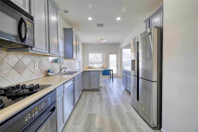 kitchen with visible vents, light countertops, decorative backsplash, black appliances, and a sink