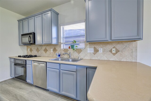 kitchen featuring decorative backsplash, black appliances, light countertops, and a sink