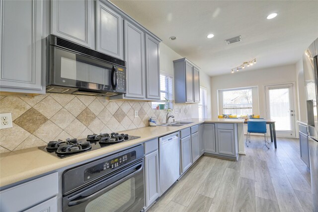 kitchen with visible vents, gray cabinetry, decorative backsplash, black appliances, and a sink