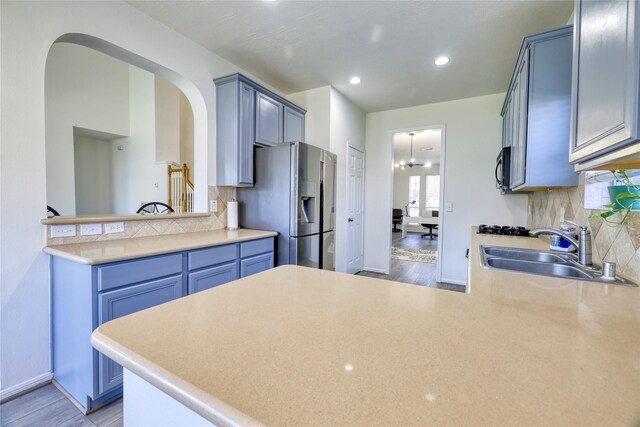 kitchen with a sink, light wood-style floors, a peninsula, and stainless steel fridge with ice dispenser