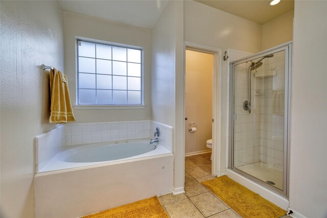 bathroom featuring tile patterned flooring, a garden tub, toilet, and a stall shower