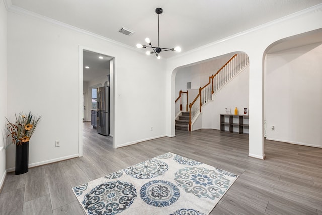 17614 Wind Mist Ln, Cypress, TX 77433 - unfurnished living room with arched walkways, crown molding, wood finished floors, stairway, and a chandelier