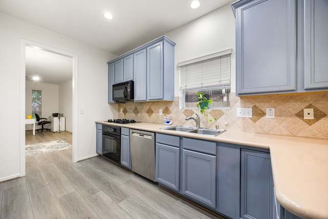 17614 Wind Mist Ln, Cypress, TX 77433 - kitchen featuring black appliances, a sink, light countertops, backsplash, and light wood-type flooring