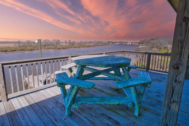 deck at dusk featuring a water view