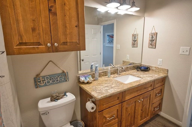 half bath featuring vanity, toilet, and baseboards