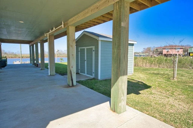 view of patio / terrace with an outbuilding, a water view, and a shed