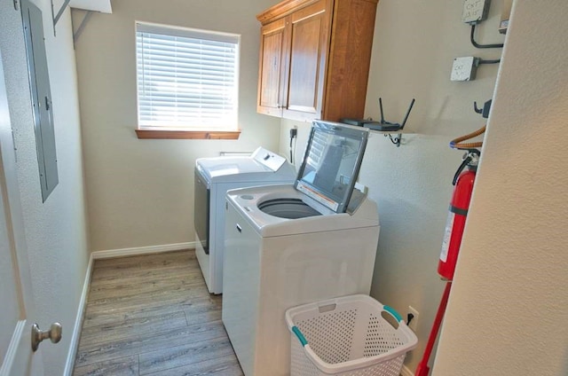 washroom featuring cabinet space, light wood-style flooring, baseboards, and separate washer and dryer