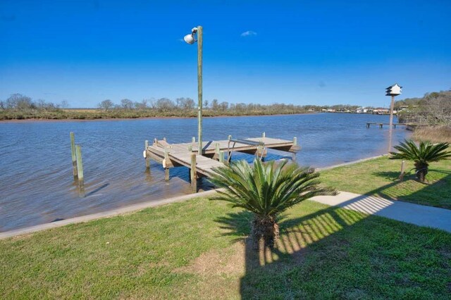 dock area with a water view and a lawn