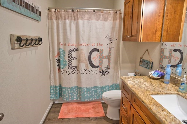 bathroom featuring toilet, curtained shower, wood finished floors, baseboards, and vanity