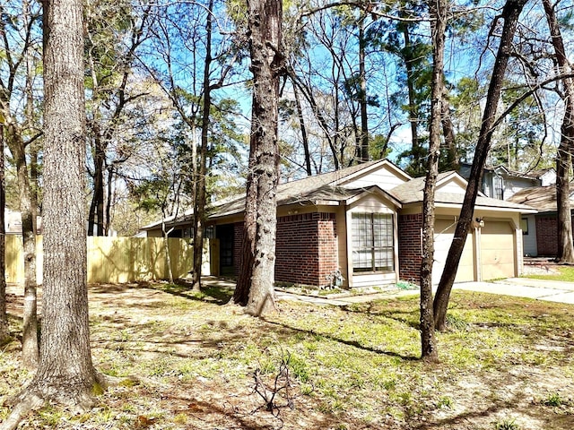 view of front facade with a garage, brick siding, driveway, and fence