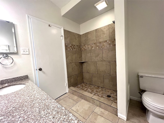 full bathroom with vanity, baseboards, a tile shower, tile patterned floors, and toilet