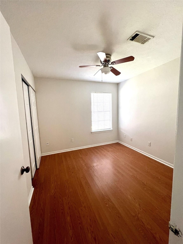 spare room featuring visible vents, wood finished floors, baseboards, and ceiling fan