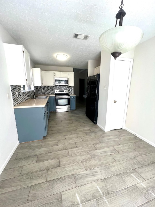 kitchen featuring visible vents, blue cabinetry, a sink, tasteful backsplash, and stainless steel appliances