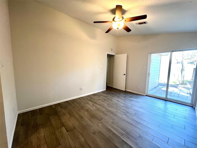 empty room with visible vents, baseboards, ceiling fan, vaulted ceiling, and dark wood-style flooring