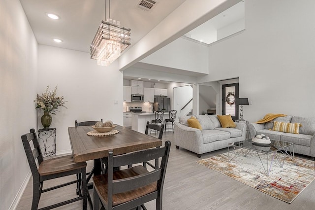 dining room featuring visible vents, stairs, light wood-type flooring, recessed lighting, and a notable chandelier