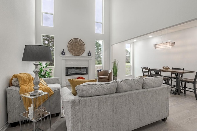 living area featuring wood finished floors, a glass covered fireplace, and a towering ceiling