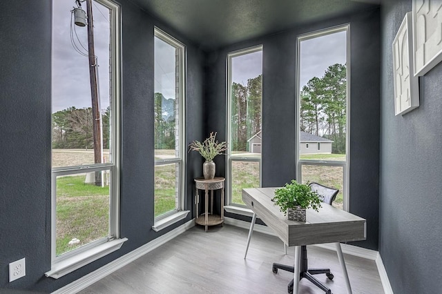 office featuring a textured wall, baseboards, and wood finished floors