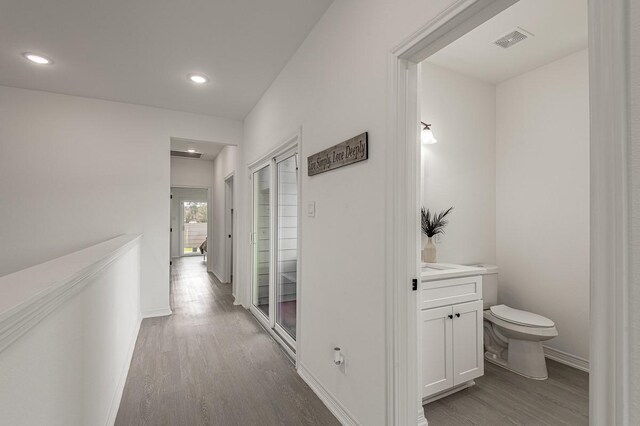 hallway with recessed lighting, visible vents, baseboards, and wood finished floors