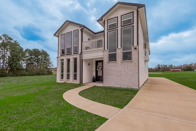 back of property featuring brick siding and a yard