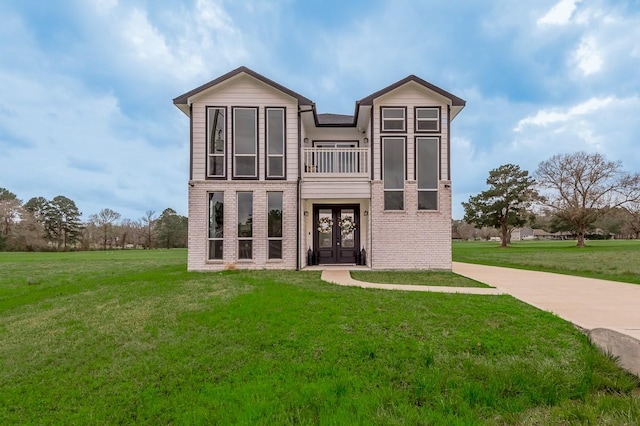 view of front of house with a front lawn, a balcony, and brick siding