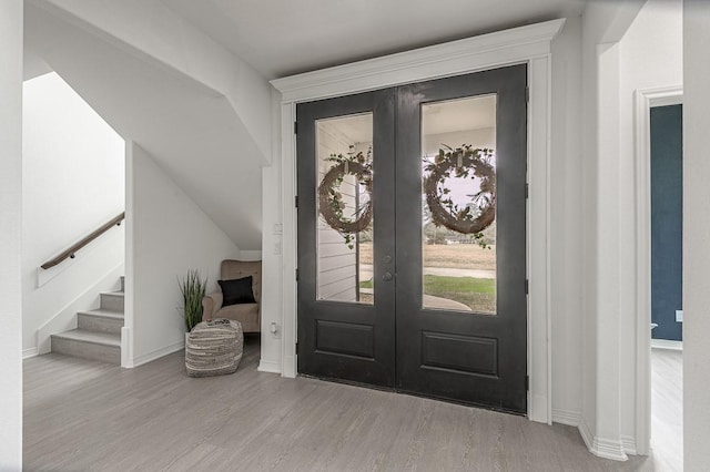 entrance foyer with baseboards, stairs, lofted ceiling, french doors, and wood finished floors