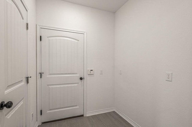 doorway with baseboards and dark wood-style flooring