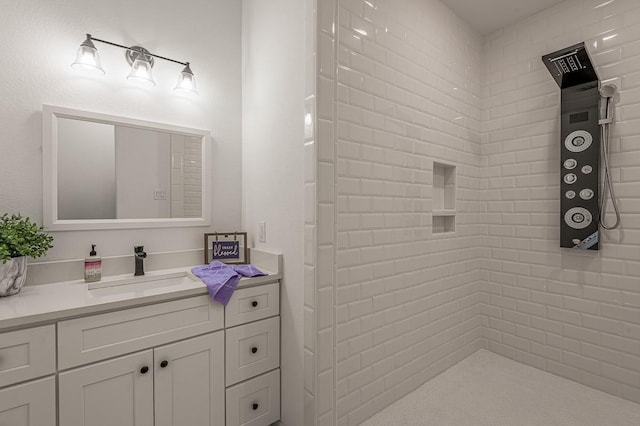 bathroom featuring tiled shower and vanity