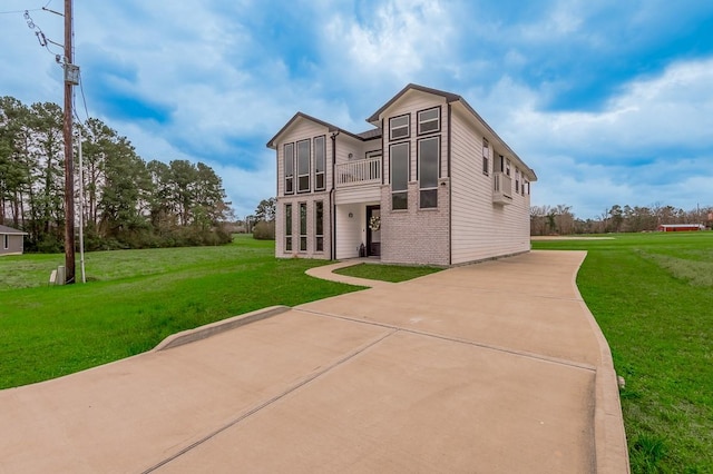 back of property with a balcony, a lawn, and brick siding