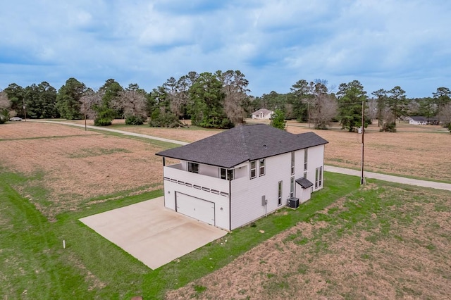 exterior space with concrete driveway, a yard, a garage, and central AC