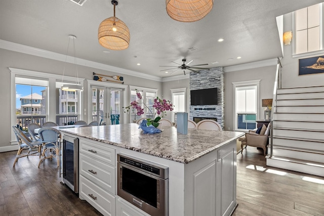 kitchen with dark wood-style floors, a healthy amount of sunlight, beverage cooler, and crown molding