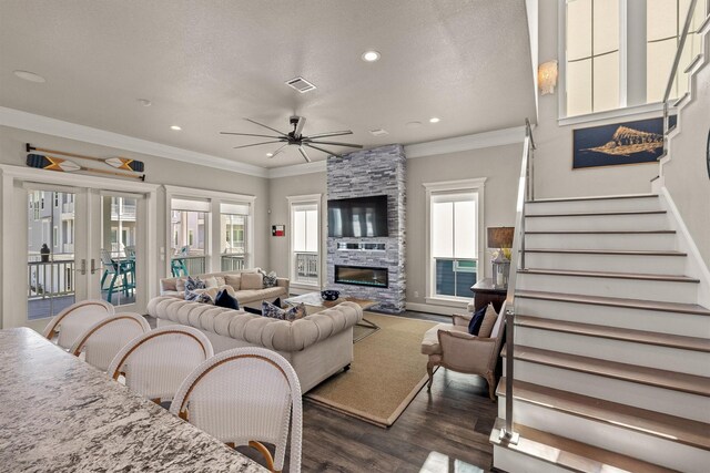 living area with stairway, wood finished floors, a fireplace, ceiling fan, and ornamental molding