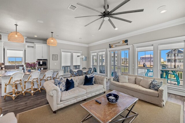 living area featuring visible vents, ornamental molding, ceiling fan, and dark wood-style flooring